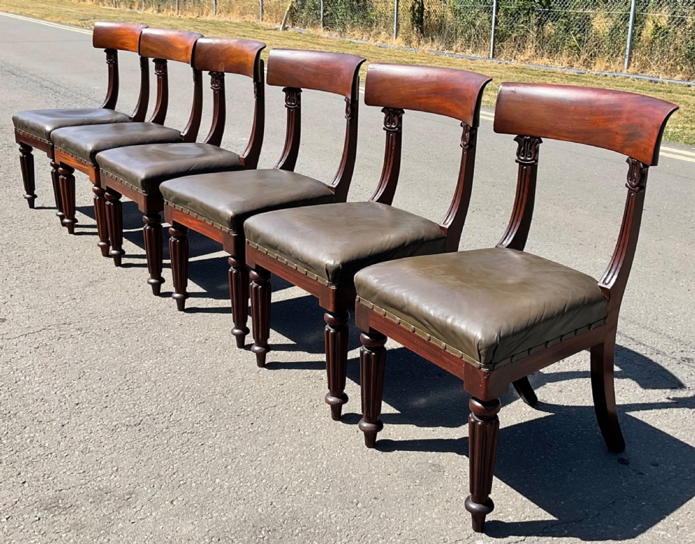 A set of six William IV mahogany dining chairs featuring curved top rails, reeded front legs, and dark green leather upholstered seats. View V