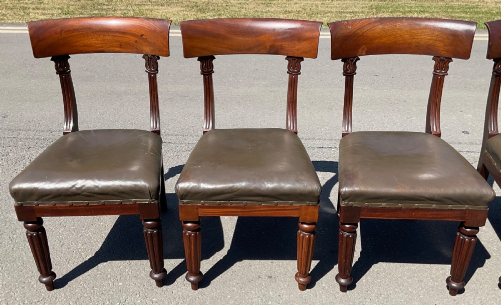 A set of six William IV mahogany dining chairs featuring curved top rails, reeded front legs, and dark green leather upholstered seats. View VII