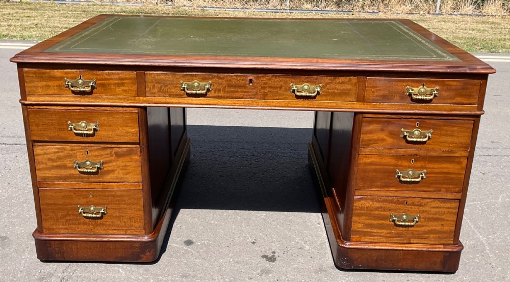 A Victorian mahogany pedestal desk featuring a green leather inset writing surface, nine drawers with brass handles, and twin pedestal bases. View II