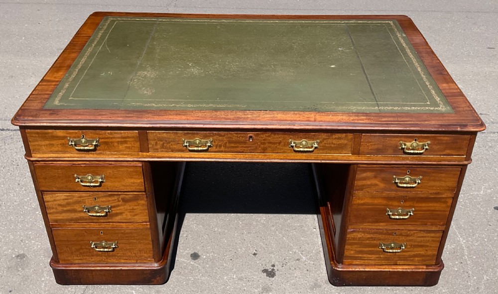 A Victorian mahogany pedestal desk featuring a green leather inset writing surface, nine drawers with brass handles, and twin pedestal bases. View III
