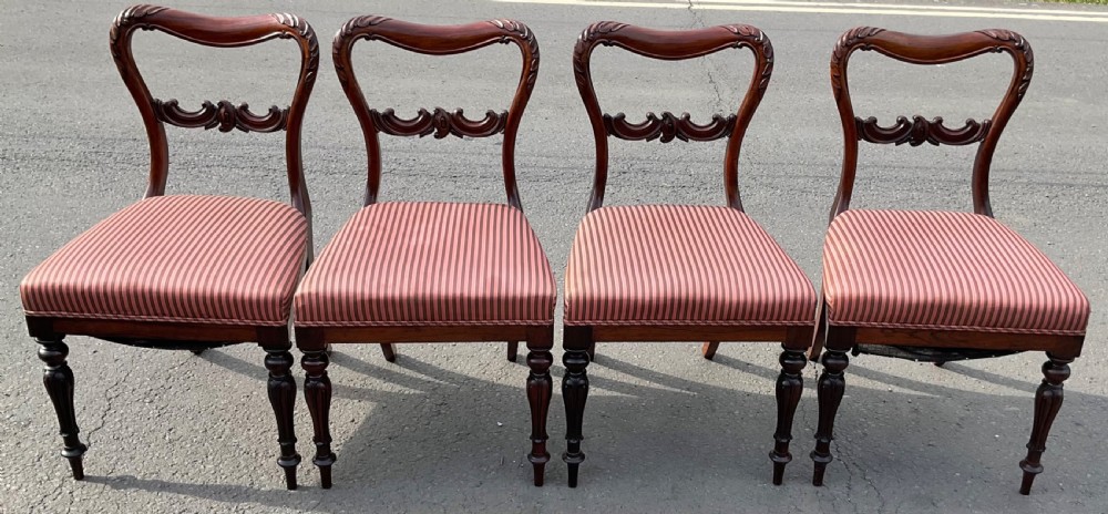 A set of four Victorian rosewood dining chairs featuring carved balloon backs, striped fabric upholstery, and turned front legs. View II