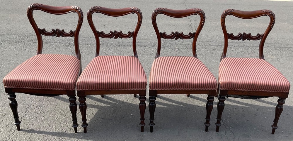 A set of four Victorian rosewood dining chairs featuring carved balloon backs, striped fabric upholstery, and turned front legs. View III