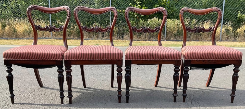 A set of four Victorian rosewood dining chairs featuring carved balloon backs, striped fabric upholstery, and turned front legs. View IV
