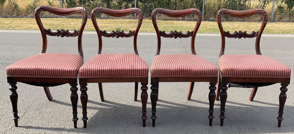 A set of four Victorian rosewood dining chairs featuring carved balloon backs, striped fabric upholstery, and turned front legs. View V