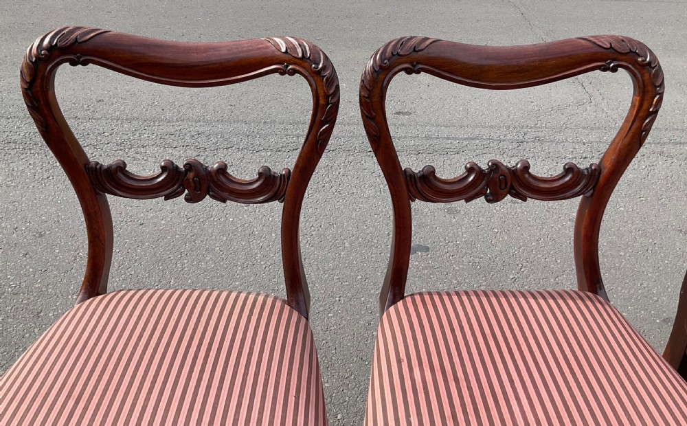 A set of four Victorian rosewood dining chairs featuring carved balloon backs, striped fabric upholstery, and turned front legs. View VI