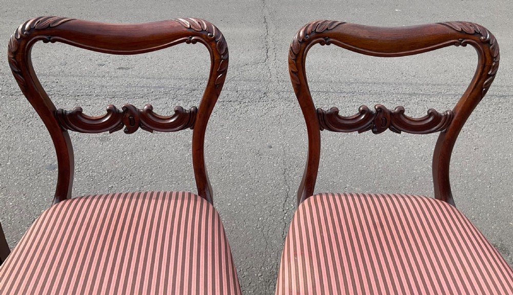 A set of four Victorian rosewood dining chairs featuring carved balloon backs, striped fabric upholstery, and turned front legs. View VII