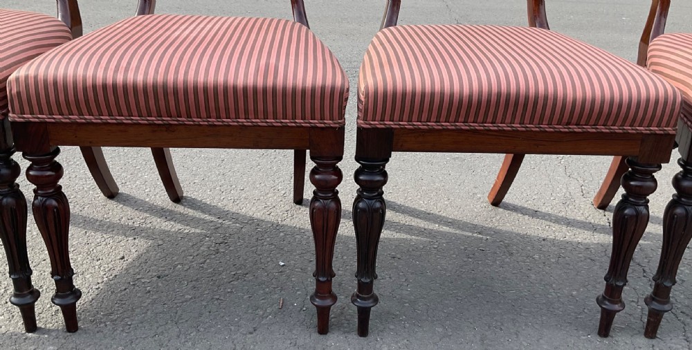 A set of four Victorian rosewood dining chairs featuring carved balloon backs, striped fabric upholstery, and turned front legs. View VIII