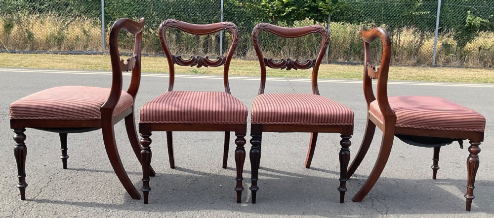 A set of four Victorian rosewood dining chairs featuring carved balloon backs, striped fabric upholstery, and turned front legs. View X