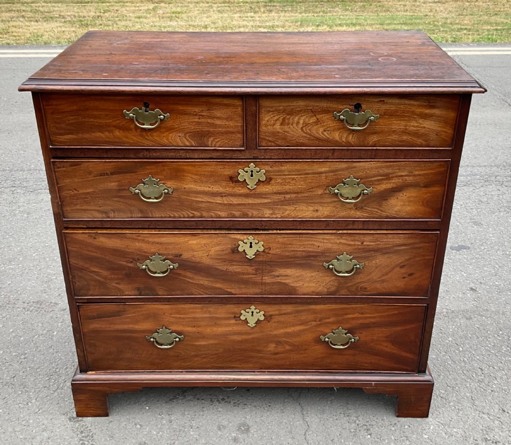 A Georgian mahogany chest of drawers featuring a two short over three long drawer arrangement with brass handles and bracket feet.