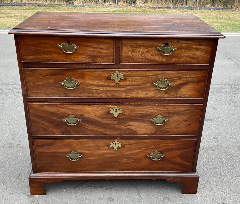 A Georgian mahogany chest of drawers featuring a two short over three long drawer arrangement with brass handles and bracket feet. View V