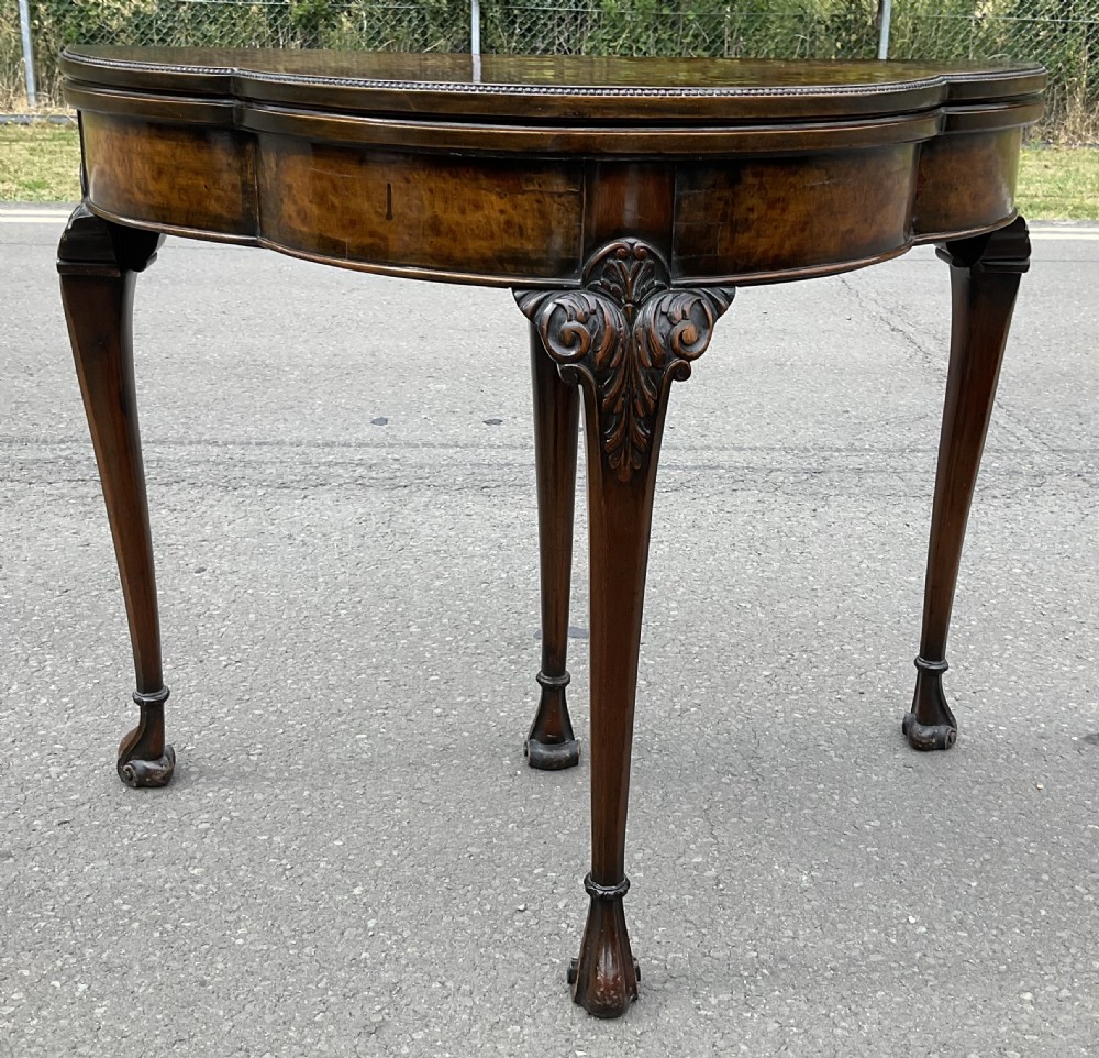 A Queen Anne style walnut foldover card table featuring a shaped top, carved cabriole legs, and claw and ball feet. View III