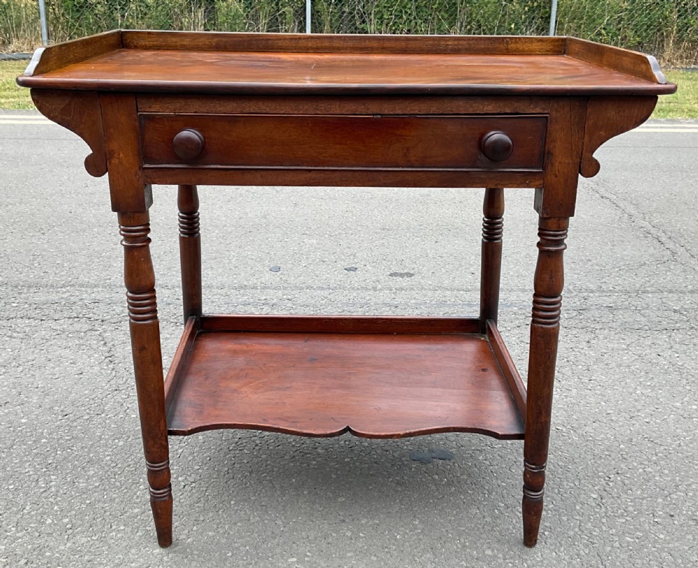 A Victorian mahogany side table featuring a galleried top, single drawer with wooden knobs, turned legs, and a scalloped lower shelf. View V