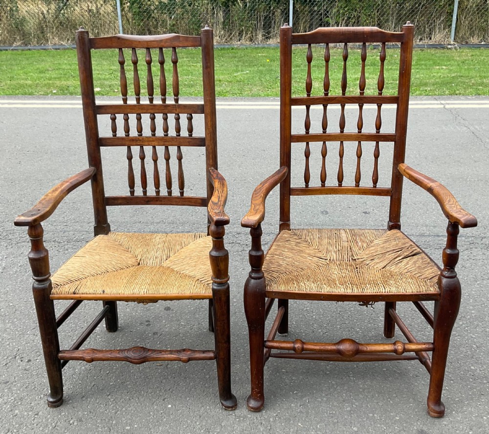 Pair of antique warm brown elm armchairs featuring tiered turned spindle backs and woven rush seats.