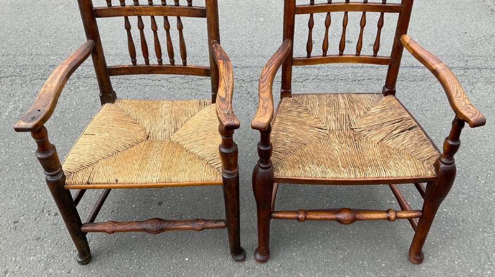 Pair of antique warm brown elm armchairs featuring tiered turned spindle backs and woven rush seats. View III
