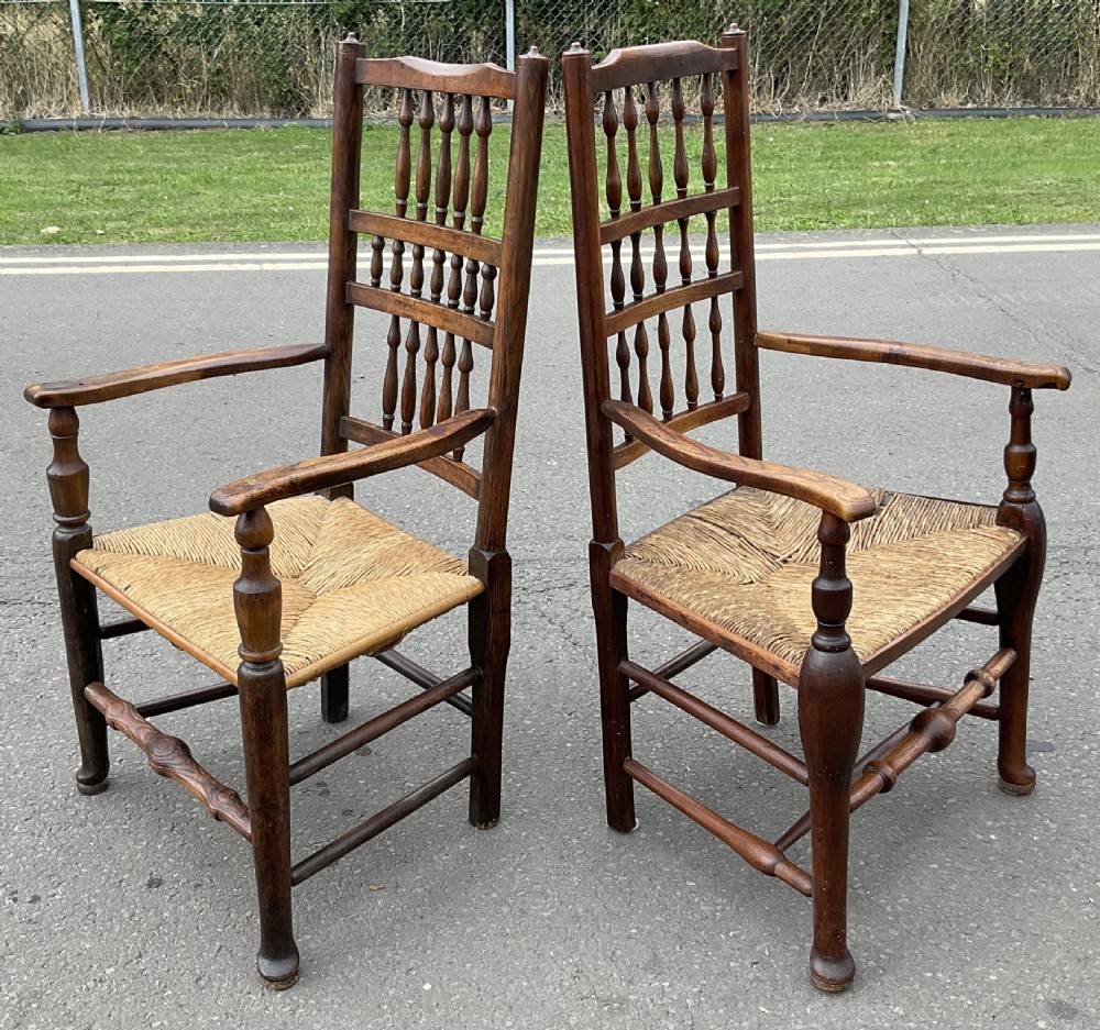 Pair of antique warm brown elm armchairs featuring tiered turned spindle backs and woven rush seats. View V