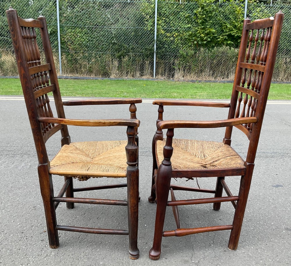 Pair of antique warm brown elm armchairs featuring tiered turned spindle backs and woven rush seats. View IX