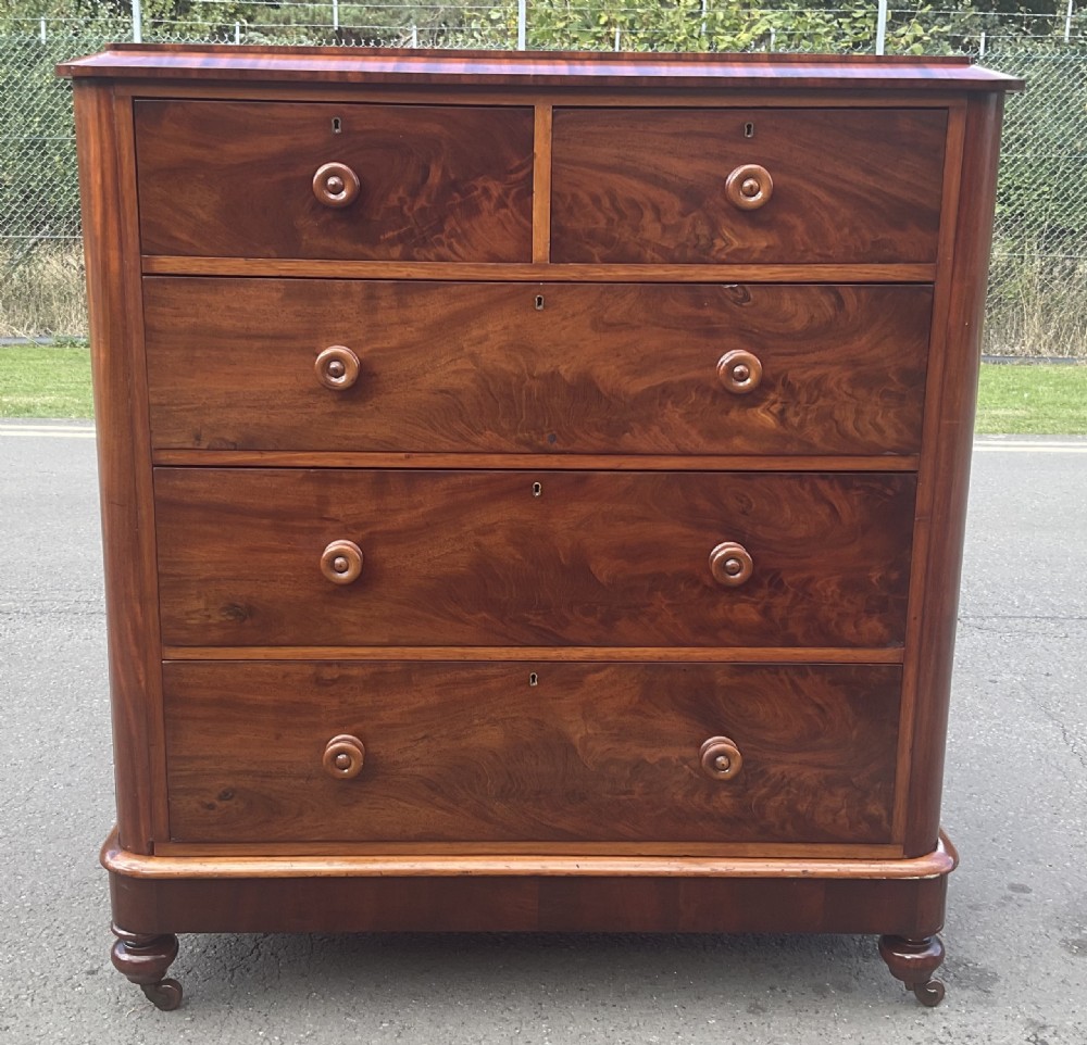 A Victorian mahogany chest of drawers featuring two short drawers over three long drawers with turned wooden knobs and flame mahogany veneer. View II