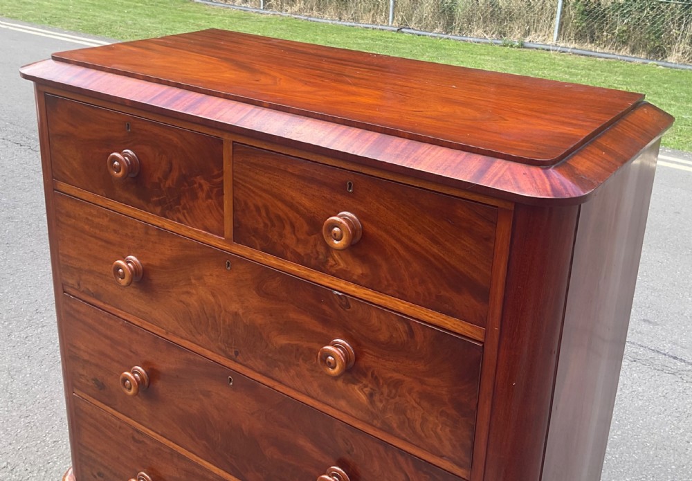 A Victorian mahogany chest of drawers featuring two short drawers over three long drawers with turned wooden knobs and flame mahogany veneer. View III