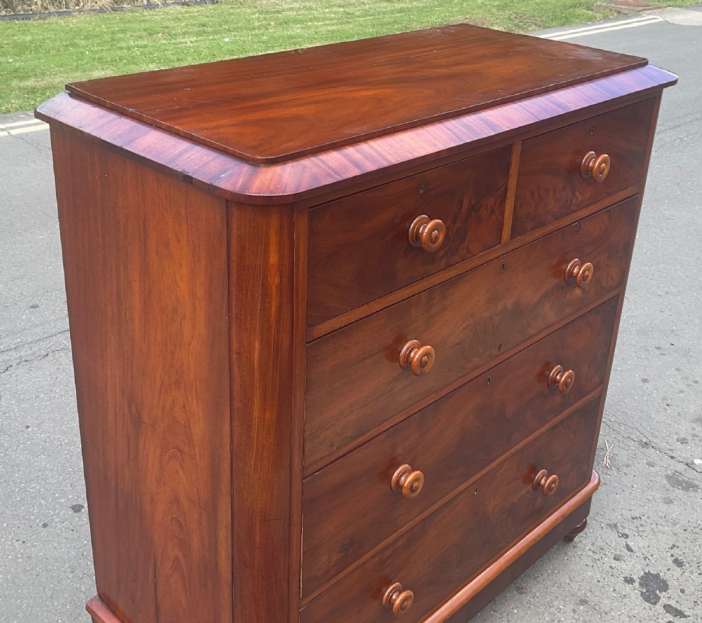 A Victorian mahogany chest of drawers featuring two short drawers over three long drawers with turned wooden knobs and flame mahogany veneer. View VII
