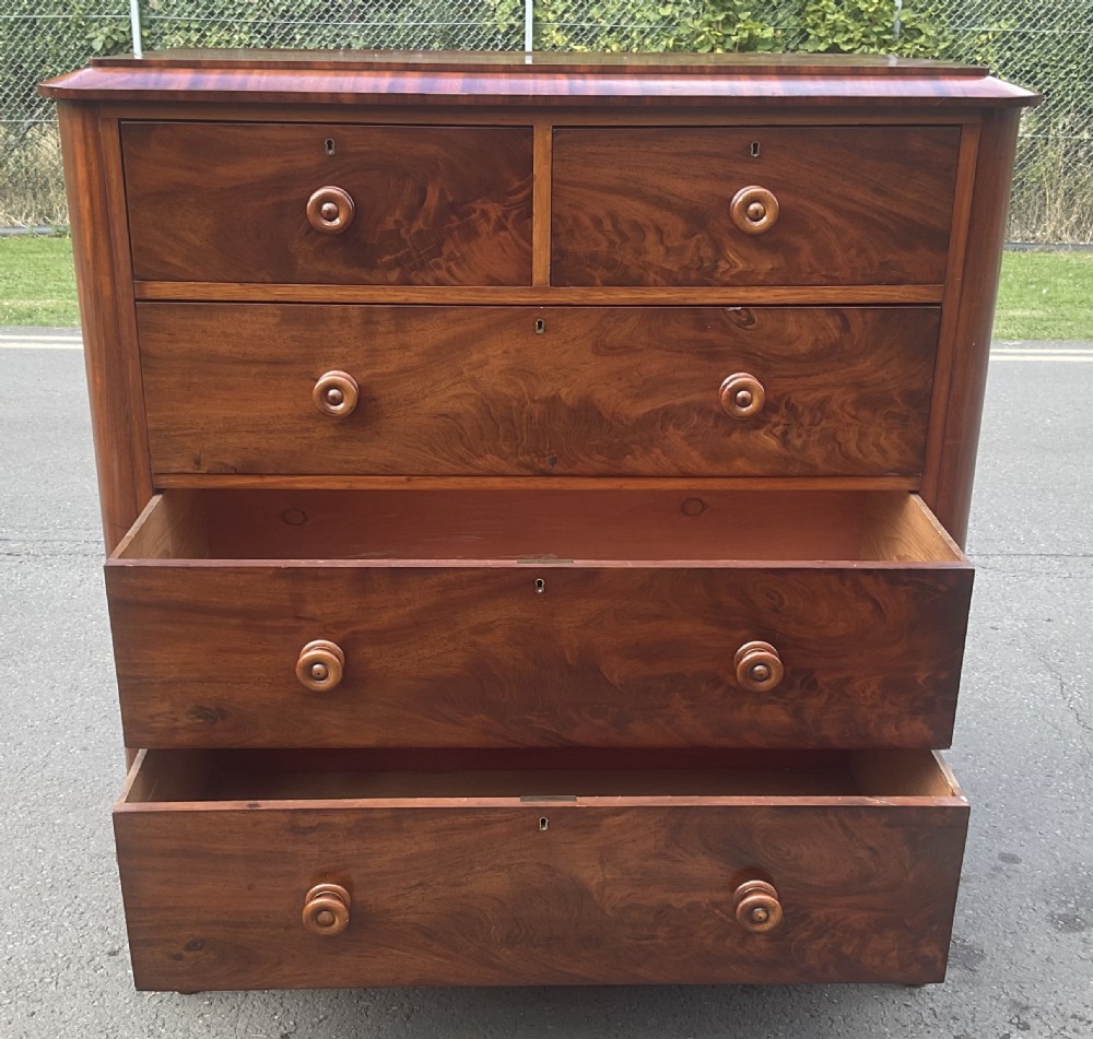A Victorian mahogany chest of drawers featuring two short drawers over three long drawers with turned wooden knobs and flame mahogany veneer. View IX