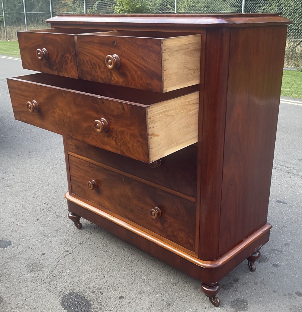 A Victorian mahogany chest of drawers featuring two short drawers over three long drawers with turned wooden knobs and flame mahogany veneer. View XIV