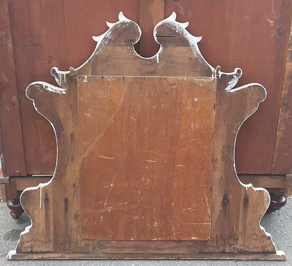 An Edwardian cream painted overmantel mirror with an arched glass centre, carved gold accent flourishes, and two small side display shelves. View VI