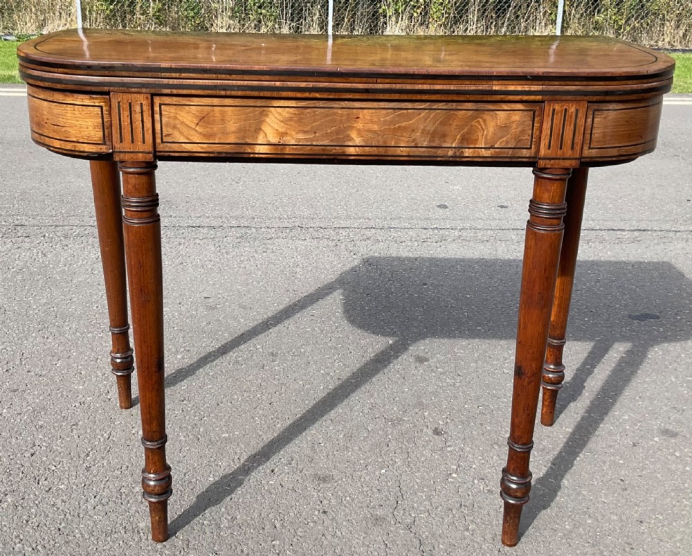 A Georgian mahogany foldover card table featuring line inlay on the frieze and slender turned legs.