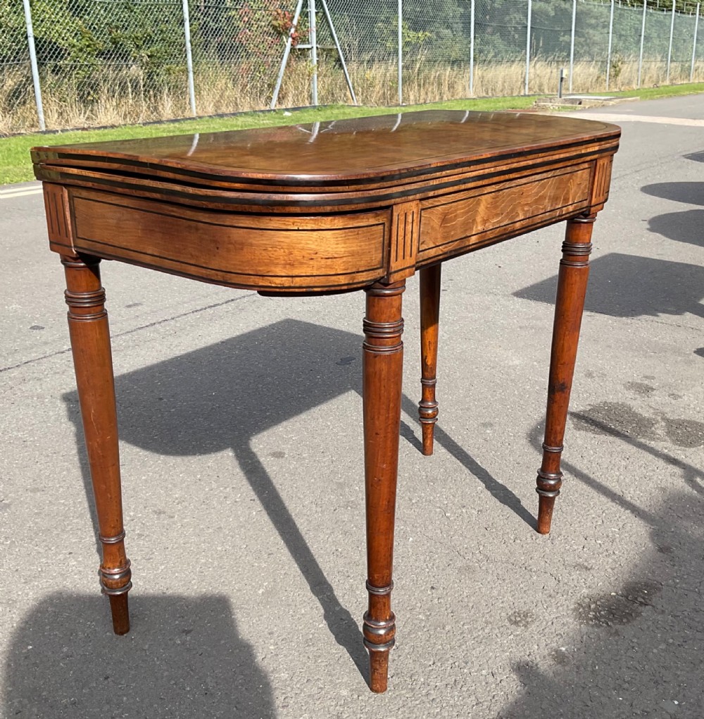 A Georgian mahogany foldover card table featuring line inlay on the frieze and slender turned legs. View VI