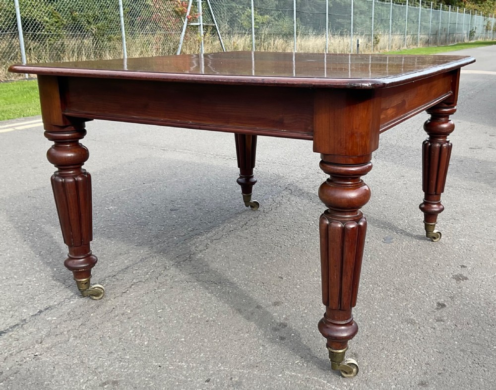 A large William IV mahogany extending dining table with a rectangular top, rounded corners, and reeded turned legs on brass castors. View XI