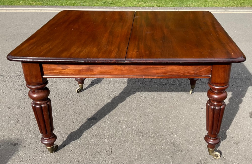 A large William IV mahogany extending dining table with a rectangular top, rounded corners, and reeded turned legs on brass castors. View XIII