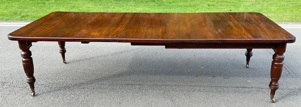 A long Victorian mahogany extending dining table with three insert leaves, rounded corners, and turned legs with brass castors. View III