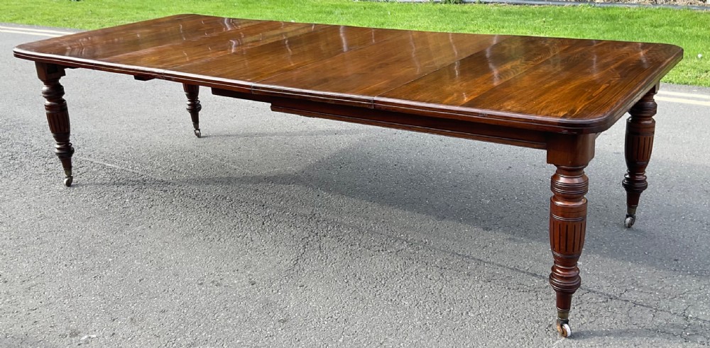 A long Victorian mahogany extending dining table with three insert leaves, rounded corners, and turned legs with brass castors. View IV