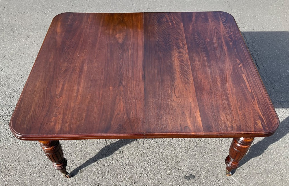 A long Victorian mahogany extending dining table with three insert leaves, rounded corners, and turned legs with brass castors. View XIII