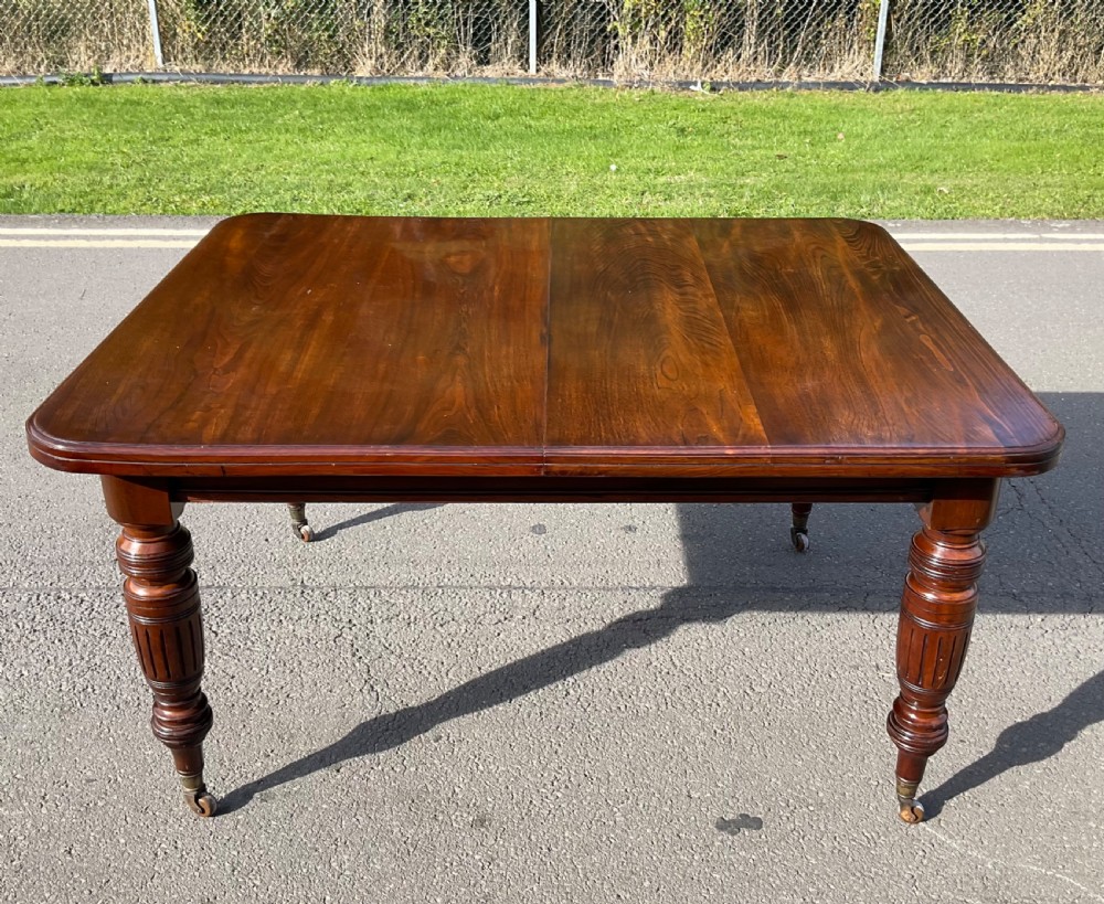 A long Victorian mahogany extending dining table with three insert leaves, rounded corners, and turned legs with brass castors. View XIV