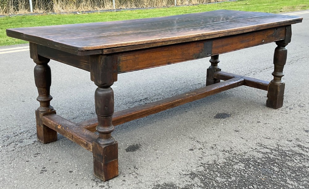 A rectangular antique oak refectory dining table featuring a thick wooden top, turned legs, and a low H-stretcher base. View III