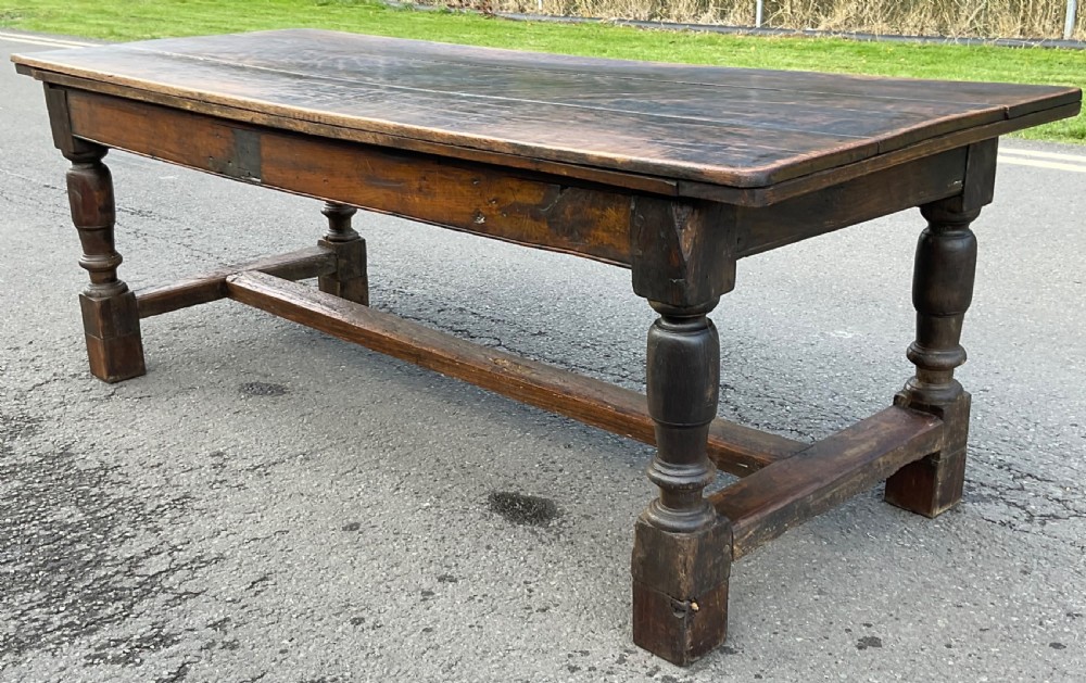 A rectangular antique oak refectory dining table featuring a thick wooden top, turned legs, and a low H-stretcher base. View IV