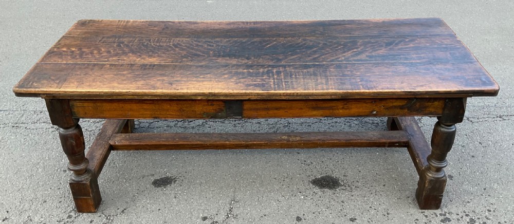 A rectangular antique oak refectory dining table featuring a thick wooden top, turned legs, and a low H-stretcher base. View VI