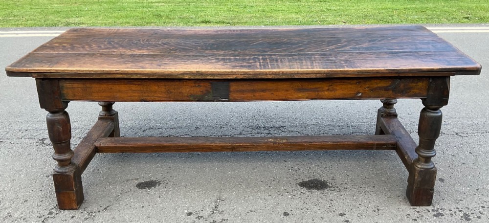 A rectangular antique oak refectory dining table featuring a thick wooden top, turned legs, and a low H-stretcher base. View VII