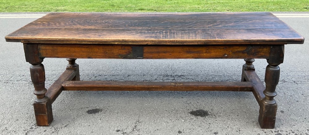 A rectangular antique oak refectory dining table featuring a thick wooden top, turned legs, and a low H-stretcher base. View VIII