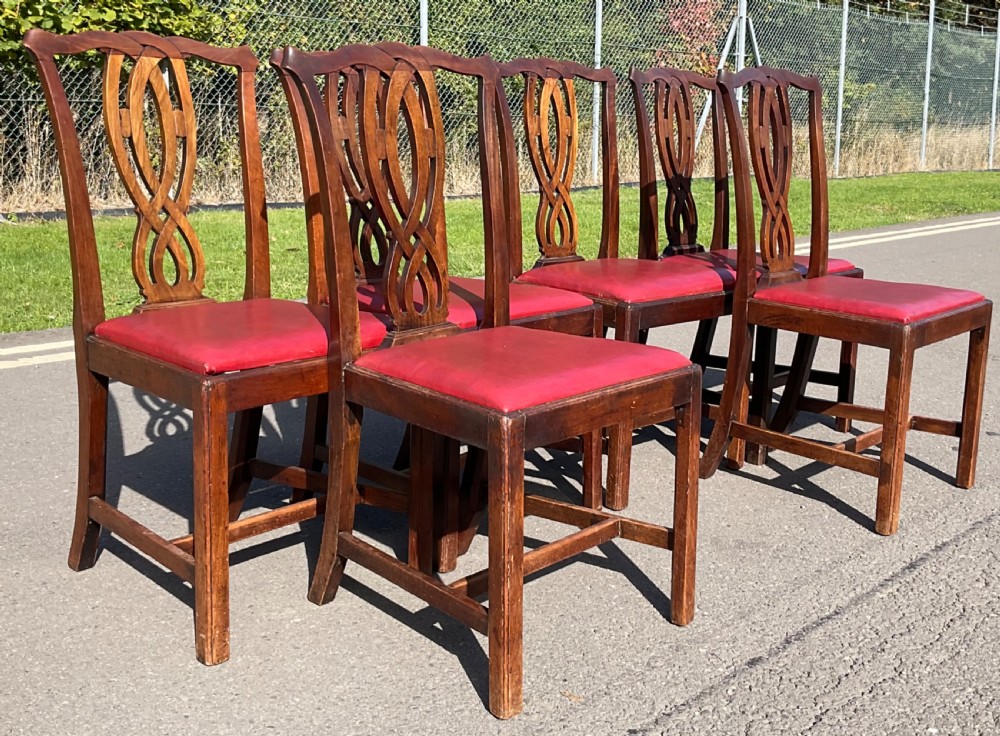 A set of six Georgian mahogany side chairs featuring pierced ribbon-carved back splats, square legs with stretchers, and red leather upholstered seats. View V