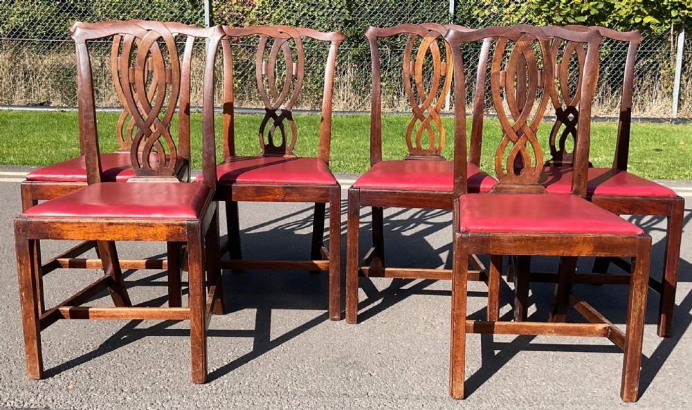 A set of six Georgian mahogany side chairs featuring pierced ribbon-carved back splats, square legs with stretchers, and red leather upholstered seats. View VI