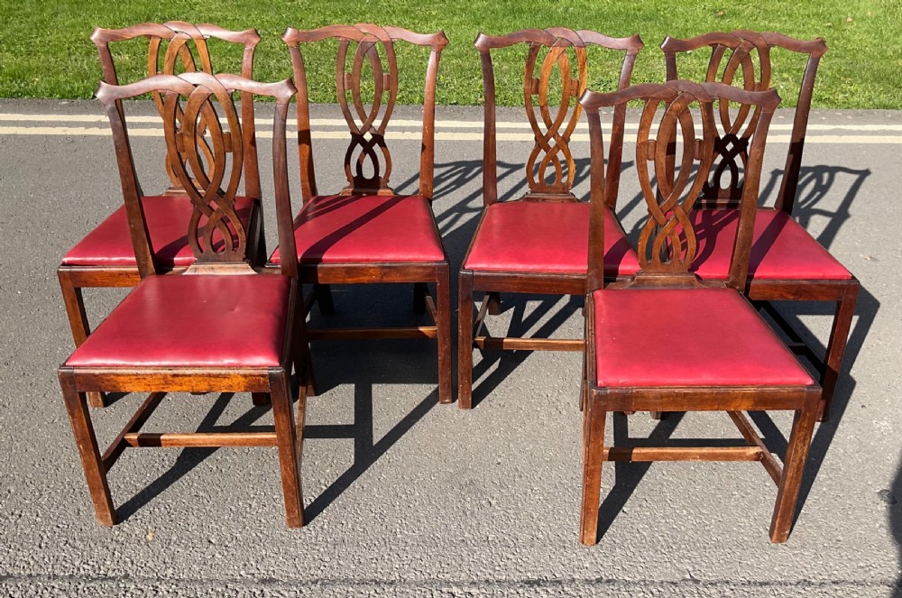 A set of six Georgian mahogany side chairs featuring pierced ribbon-carved back splats, square legs with stretchers, and red leather upholstered seats. View VII