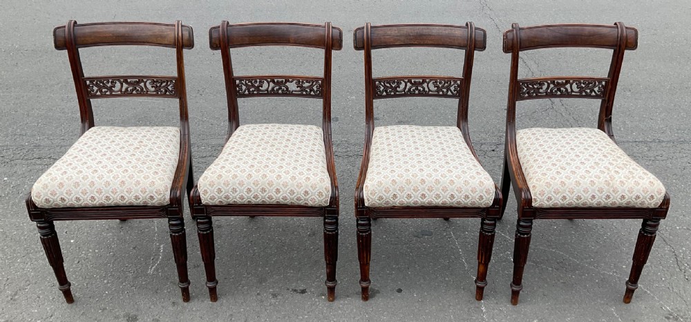 A set of four antique William IV dark rosewood dining chairs with carved mid-rails, turned front legs, and light-patterned upholstered seats.