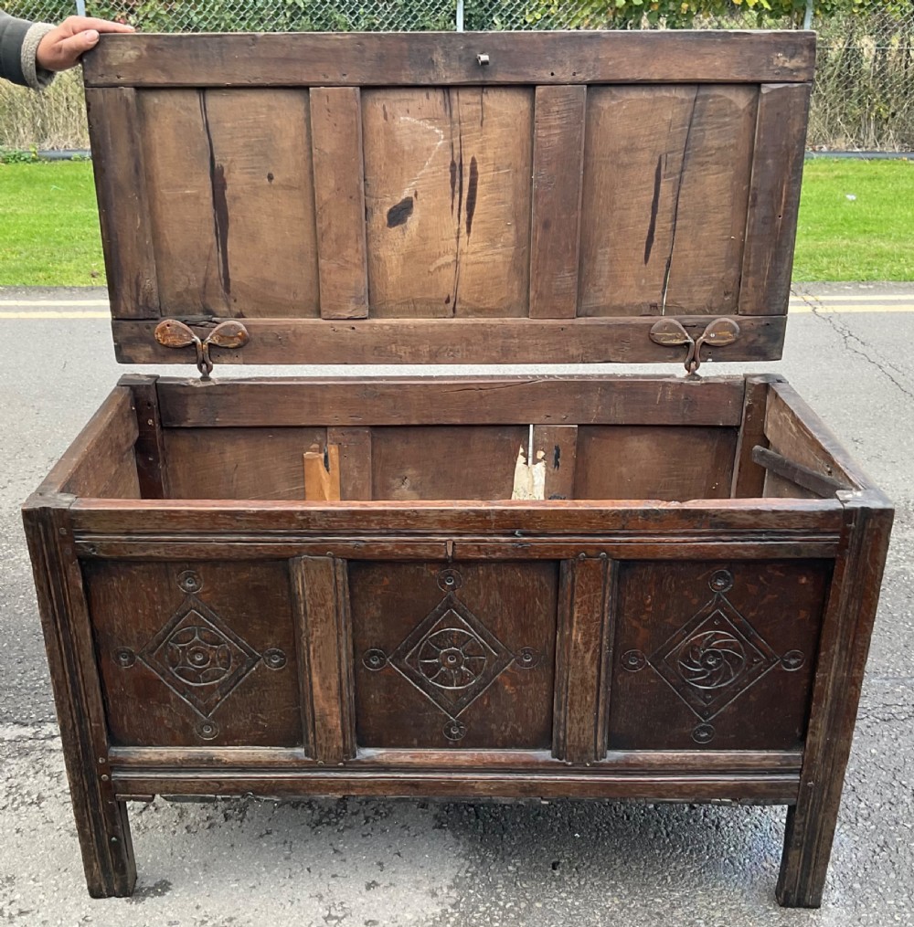 A dark carved oak blanket chest featuring three panelled sections with geometric lozenge carvings. View XII