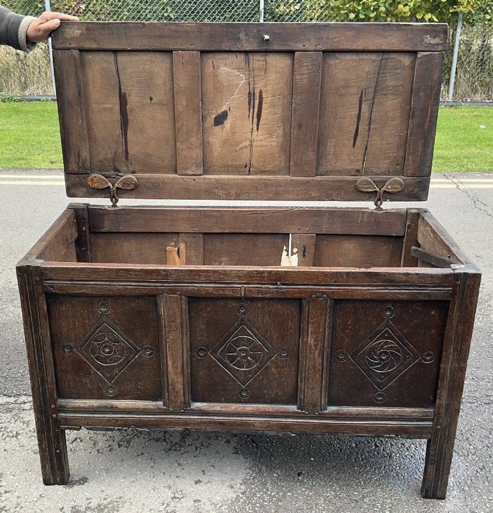A dark carved oak blanket chest featuring three panelled sections with geometric lozenge carvings. View XIII