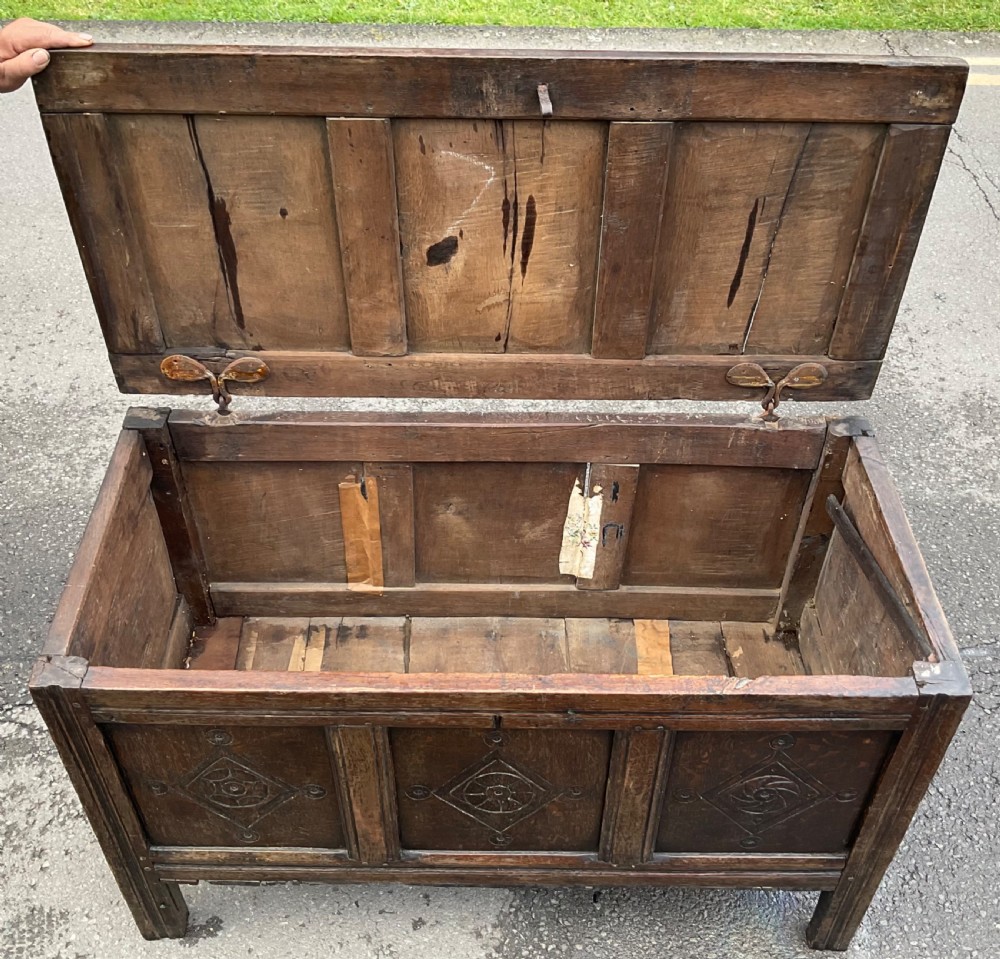 A dark carved oak blanket chest featuring three panelled sections with geometric lozenge carvings. View XIV