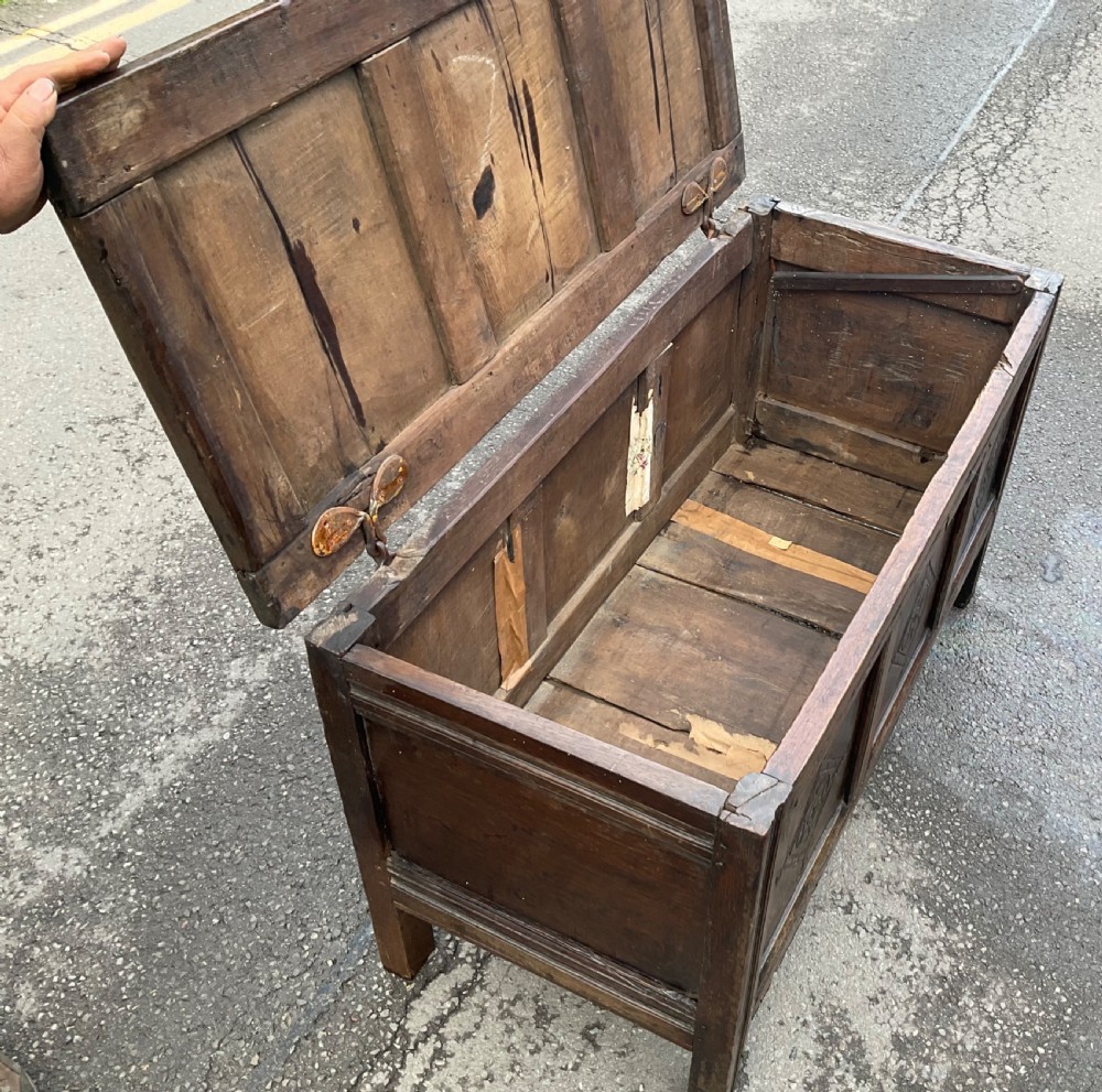 A dark carved oak blanket chest featuring three panelled sections with geometric lozenge carvings. View XV