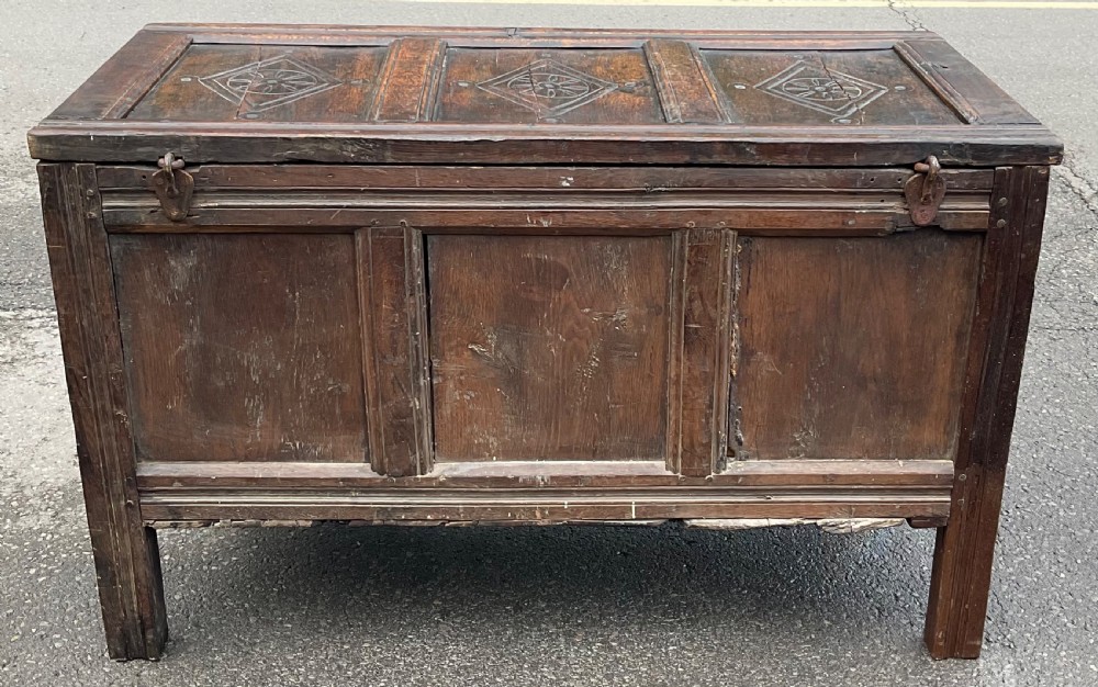 A dark carved oak blanket chest featuring three panelled sections with geometric lozenge carvings. View XVII