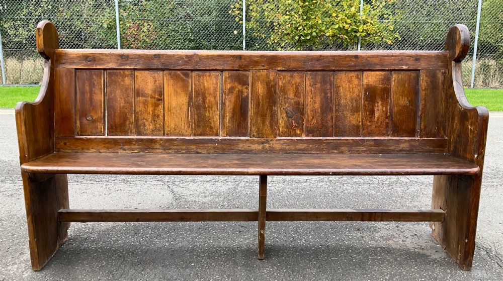 A Victorian pine church pew bench featuring a panelled backrest, shaped side ends with rounded finials, and a warm aged finish. View II