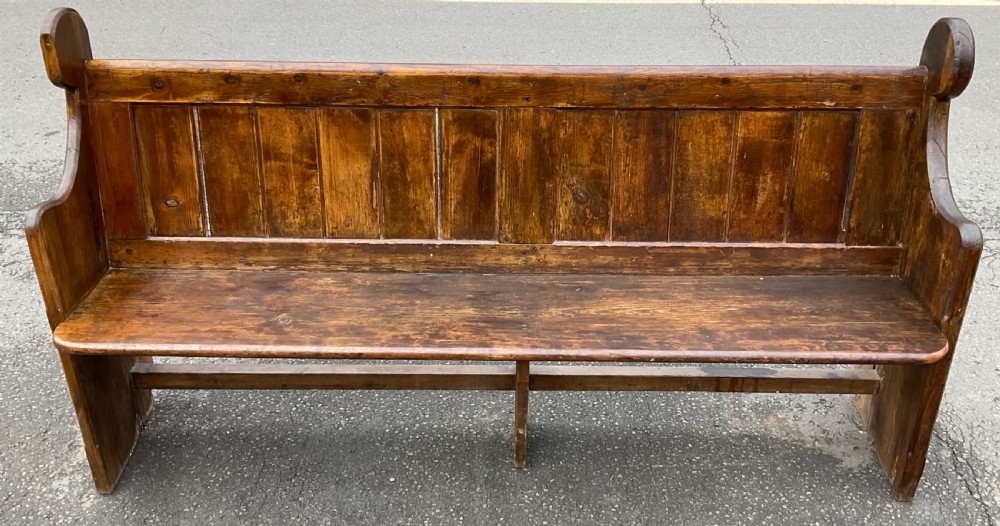 A Victorian pine church pew bench featuring a panelled backrest, shaped side ends with rounded finials, and a warm aged finish. View IV